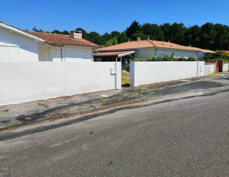 Rehaussement de qualité d'un mur de clôture en parpaing avec enduit de façade à La Teste-de-Buch