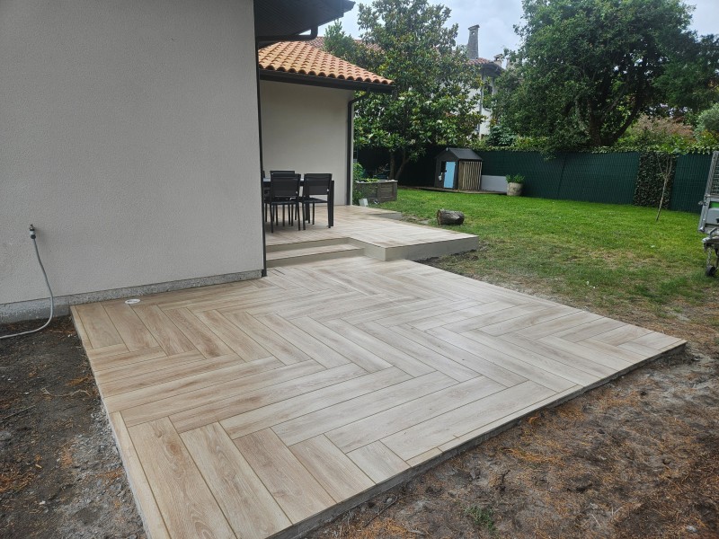 Terrasse en béton avec carrelage extérieur en continuité avec l’intérieur d’un espace situé à Mios en Gironde