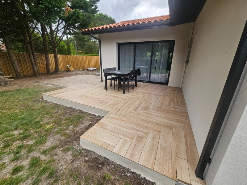 Terrasse en béton sur mesure avec carrelage extérieur en continuité avec l’intérieur d’un espace situé à Mios